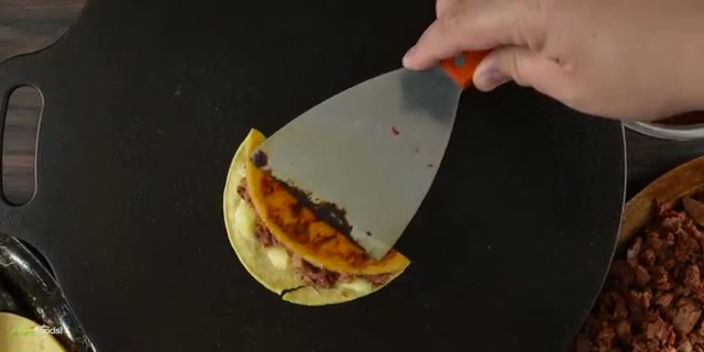 The finished crispy birria taco with melted cheese and brisket, showing the fina